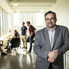 Jeffery Doshna leans on a railing inside the Tyler building, hands together, smiling at the camera.