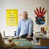  Dave MacCormack, wearing a blue shirt, stands in a design studio at Tyler, looking at the camera.