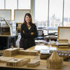Fauzia Sadiq Garcia smiling inside an architecture studio at Tyler, surrounded by build models and design materials.