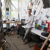 Andrew John Wit smiling, leaning on a desk with his arms crossed in a Tyler architecture studio.