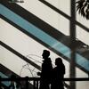 The silhouette of two students walking inside Tyler, with light from the window casting large shadows on the wall behind them.