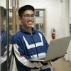 Tyler design student holding a computer and smiling.