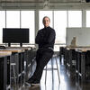 Pablo Meninato, with his arms crossed, leans on a stool while looking at the camera in an architecture studio space.