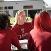 A student wearing a temple sweatshirt smiles at people.