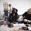 A Tyler painting student and professor in a classroom.