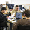 Architecture students sitting inside a Tyler studio space, working on their projects on their computer.