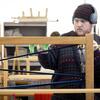 A fibers student standing behind a loom.