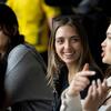 A student smiling and listening to another student next to her talk.