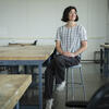 Lauren Aman sitting on a stool in a Tyler studio space, looking away from the camera.