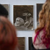 The back of students heads as they look at paintings.