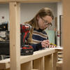 A Tyler student using using a drill to construct a wooden structure