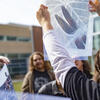 A student holding up a transparent photograph up to the sun.
