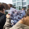A student holding up a printed photograph outside.