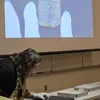 Art history professor examining an artifact displayed on the screen above her