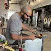 Glass artist shaping a hot glass sculpture in the studio