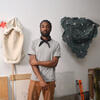 Ryan Scalis standing in the studio in front of artwork