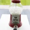 A vintage red candy machine full of ice with a padlock holding it closed. 