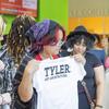 A student holds up a white Tyler School of Art and Architecture t-shirt, showcasing the design with pride. The shirt’s simple yet recognizable branding represents the school’s identity.
