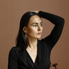 Rachelle Anayansi Mozman Solano holding a hand to her head and looking away from the camera.