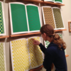 Female student with a ponytail observes a wall display featuring several open books, each displaying checkerboard patterns in various shades of green and yellow.