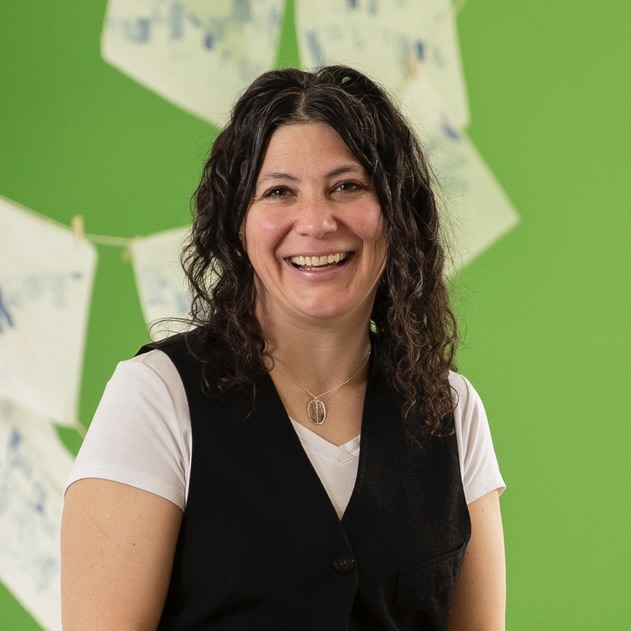 Renee Jackson sitting on a table, smiling at the camera.