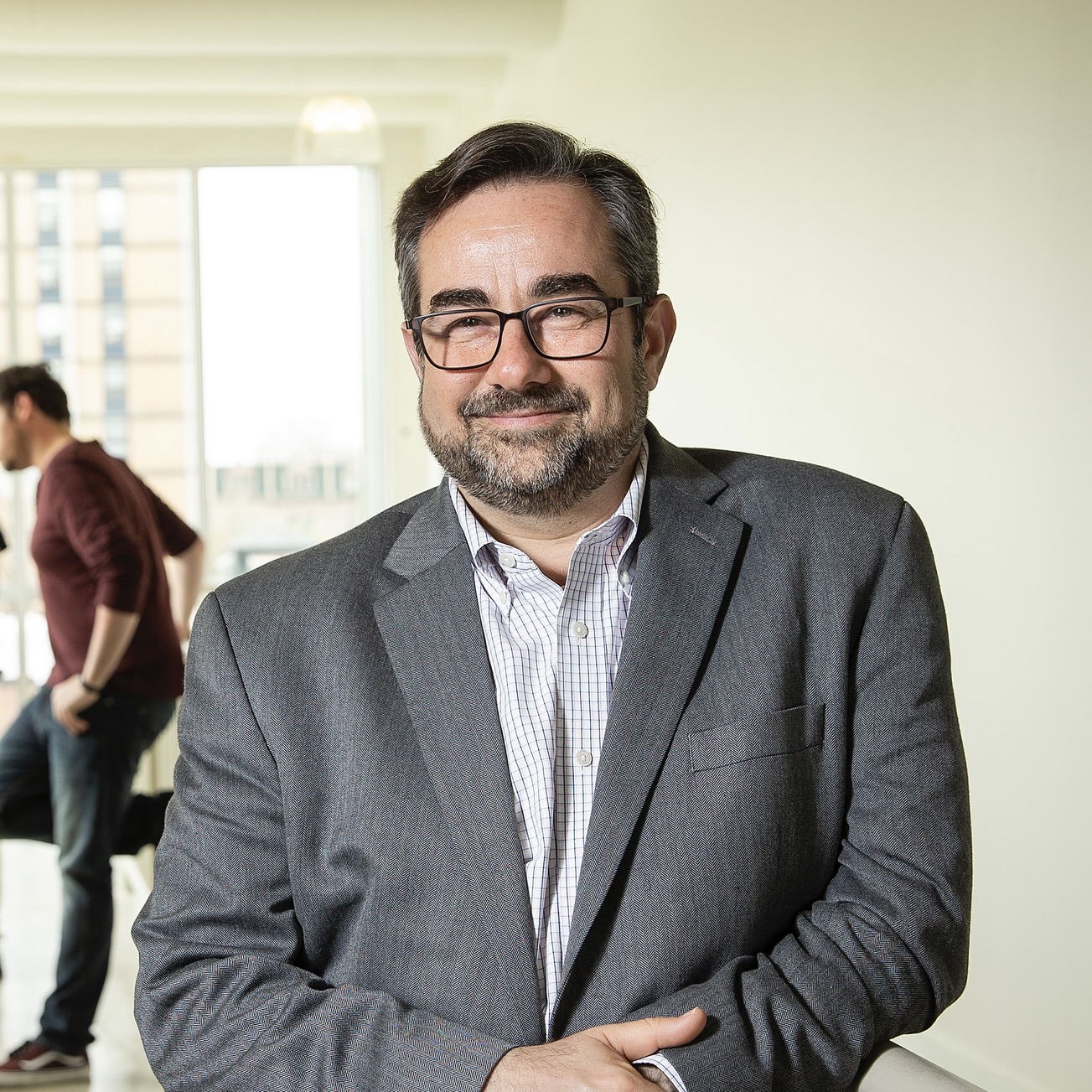 Jeffery Doshna leans on a railing inside the Tyler building, hands together, smiling at the camera.