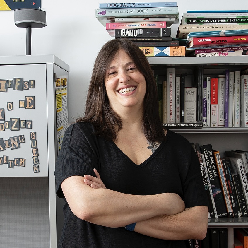 Abby Guido smiles at the camera with her arms crossed, looking relaxed and confident.