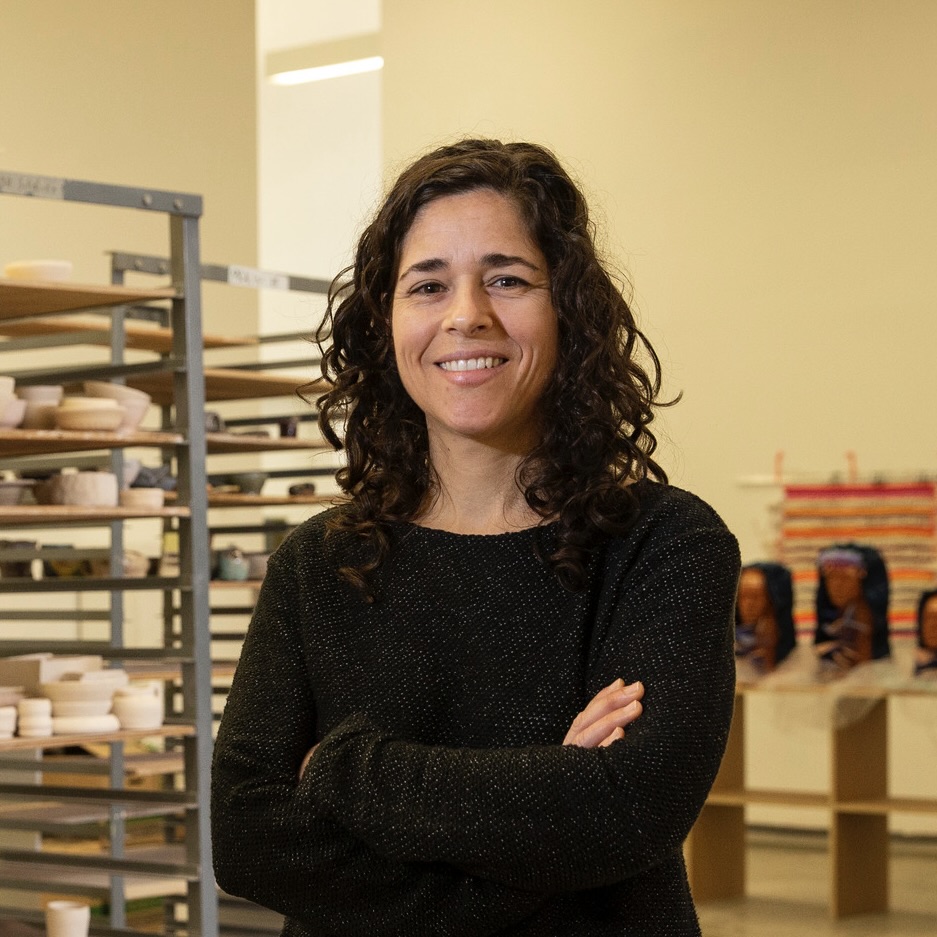 Lauren Sandler stands with her arms crossed in a ceramics studio at Tyler.